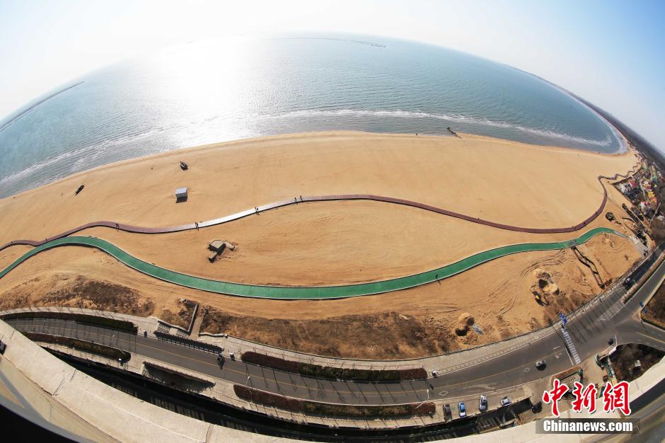 3月13日，秦皇島萬米臨海沙灘木棧道。據(jù)了解，該木棧道全長約4200米，與北戴河區(qū)原有的7500米木棧道對接后全線總長度1.17萬米，整個(gè)木棧道東起秦皇島體育基地游船碼頭，西至北戴河濕地公園，呈波浪形蜿蜒10.4公里海岸線。 中新社發(fā) 曹建雄 攝 CNSPHOTO